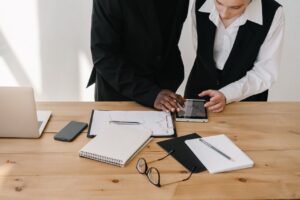 Two professionals collaborating over charts and tablet in a modern office setting.